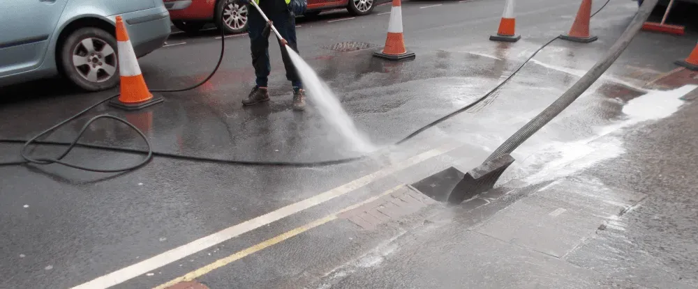 Drainage engineer performing high-pressure water jetting to unblock an external drain or gully.