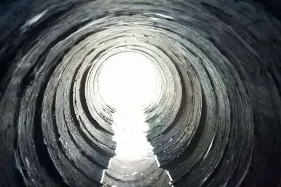 Inside a drain pipe with light at the end, suggesting a clear pipe or CCTV inspection view