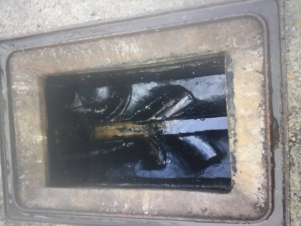 Blocked external drain with stagnant water and debris, viewed from above.