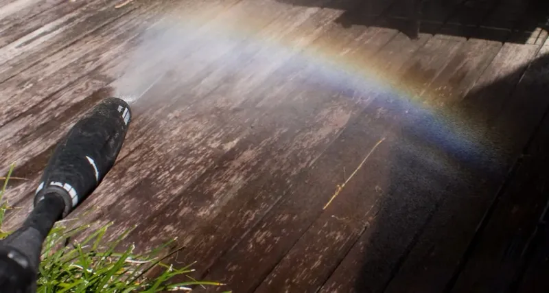 High-pressure water jetter in action, with a rainbow visible in the spray, symbolizing effective cleaning.