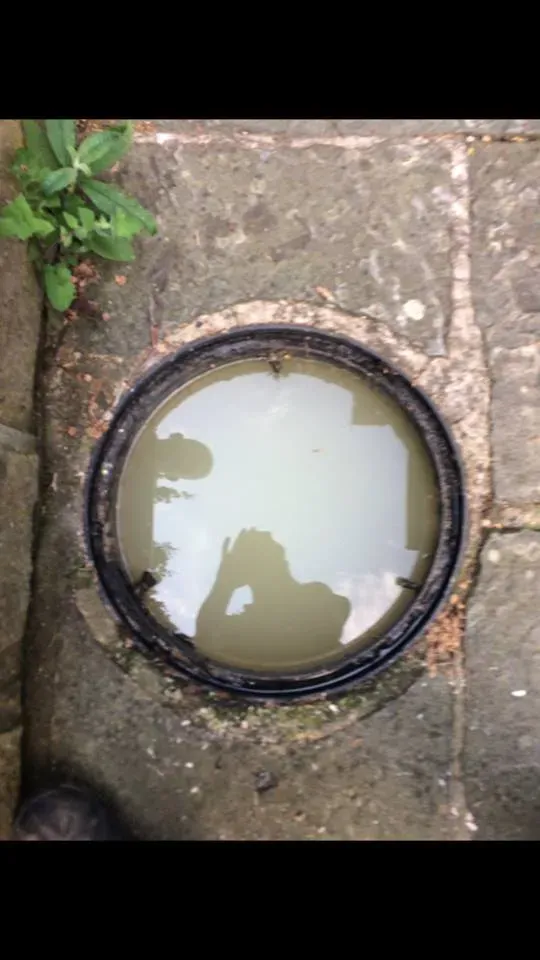 Blocked domestic manhole chamber overflowing with standing wastewater